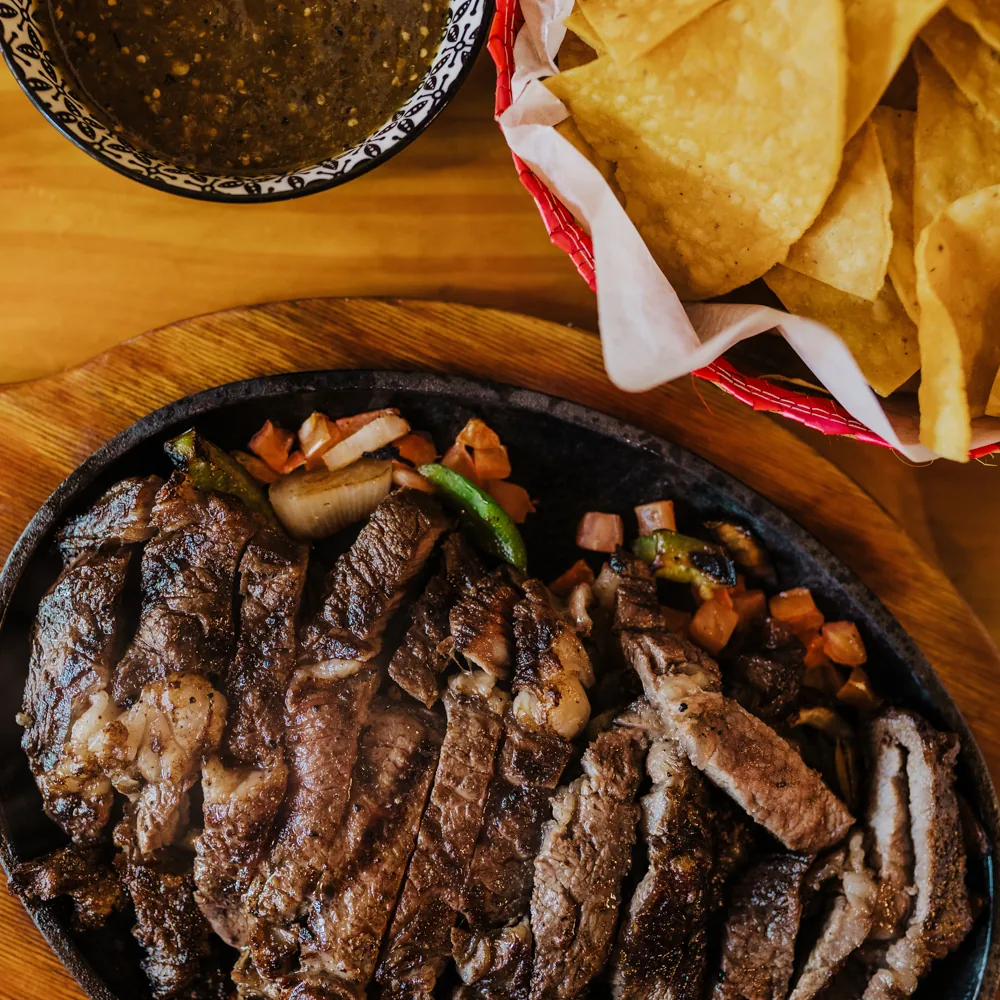 Sizzling fajita platter with chips and salsa
