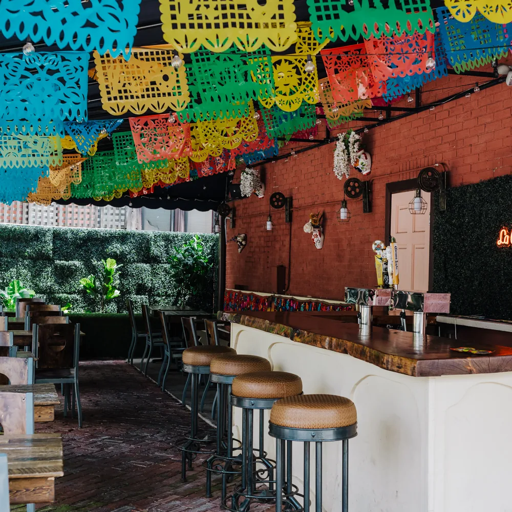 Inside La Piñata — colorful papel picado banners, rustic bar seating